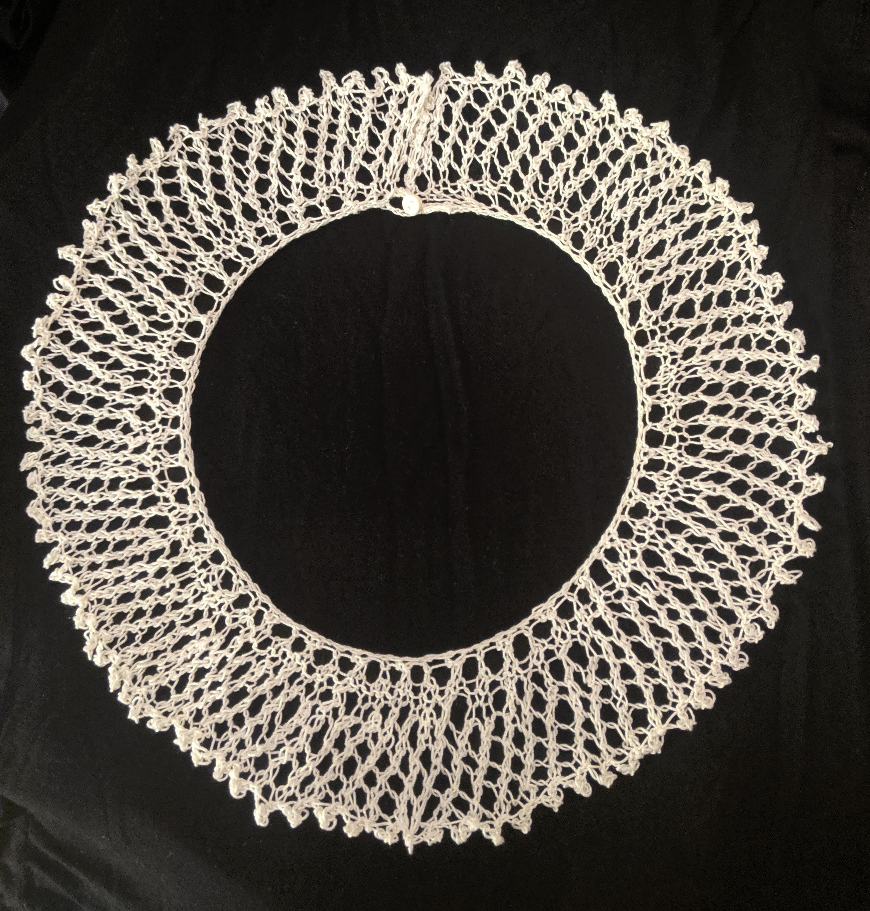 Photograph of knit collar in white yarn against black backdrop